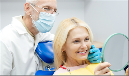 Blonde Patient looking in the mirror at her teeth with Dentist