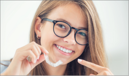 Female with glasses holding invisalign