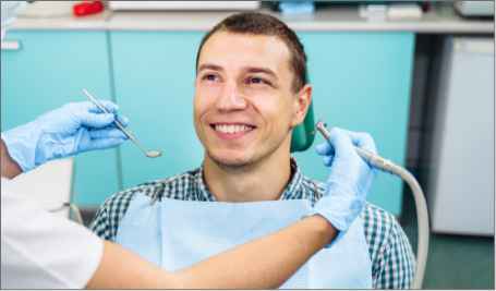 Male Patient looking at dentist holding cleaning tools